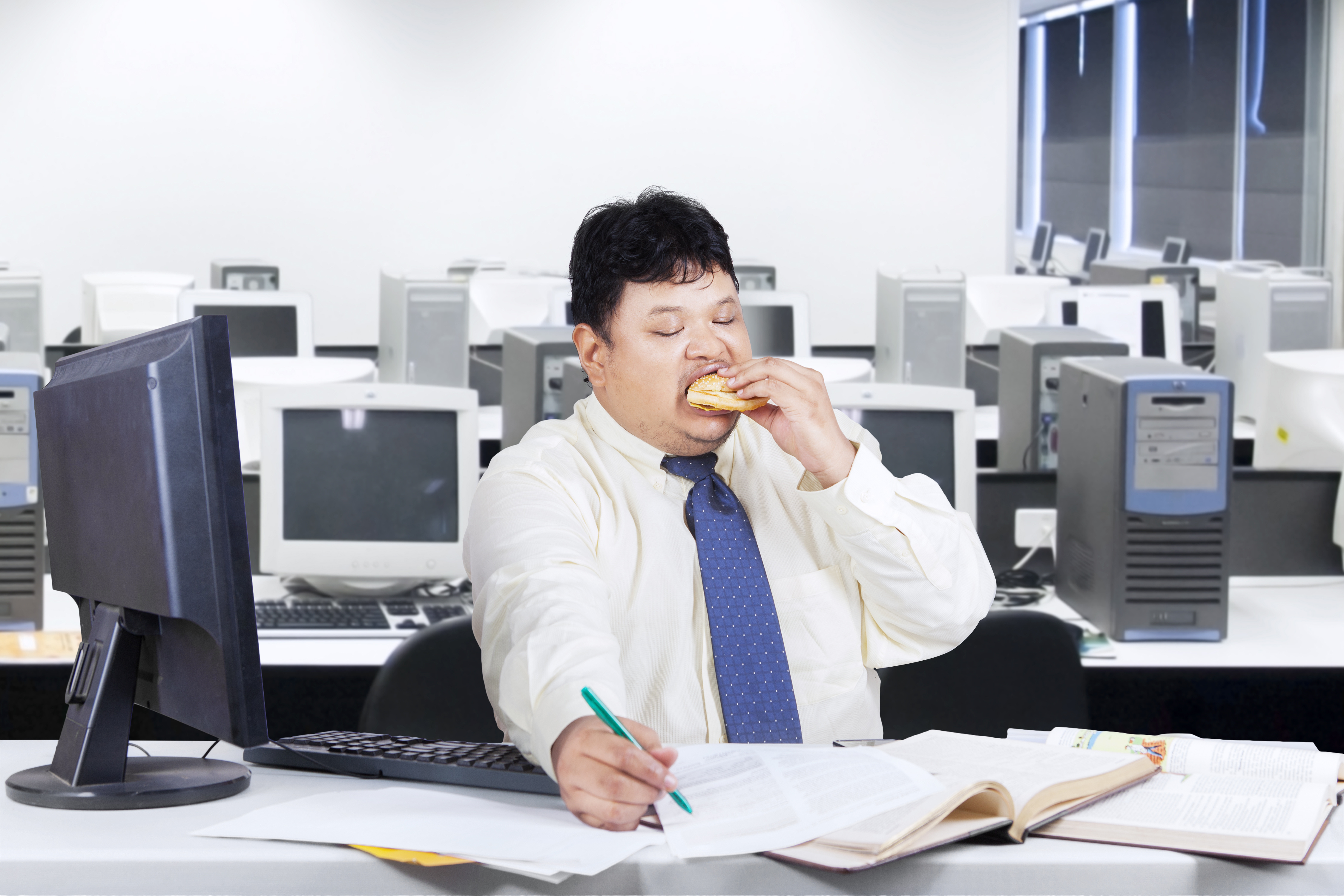 Obesity businessman working in office while eating junk food