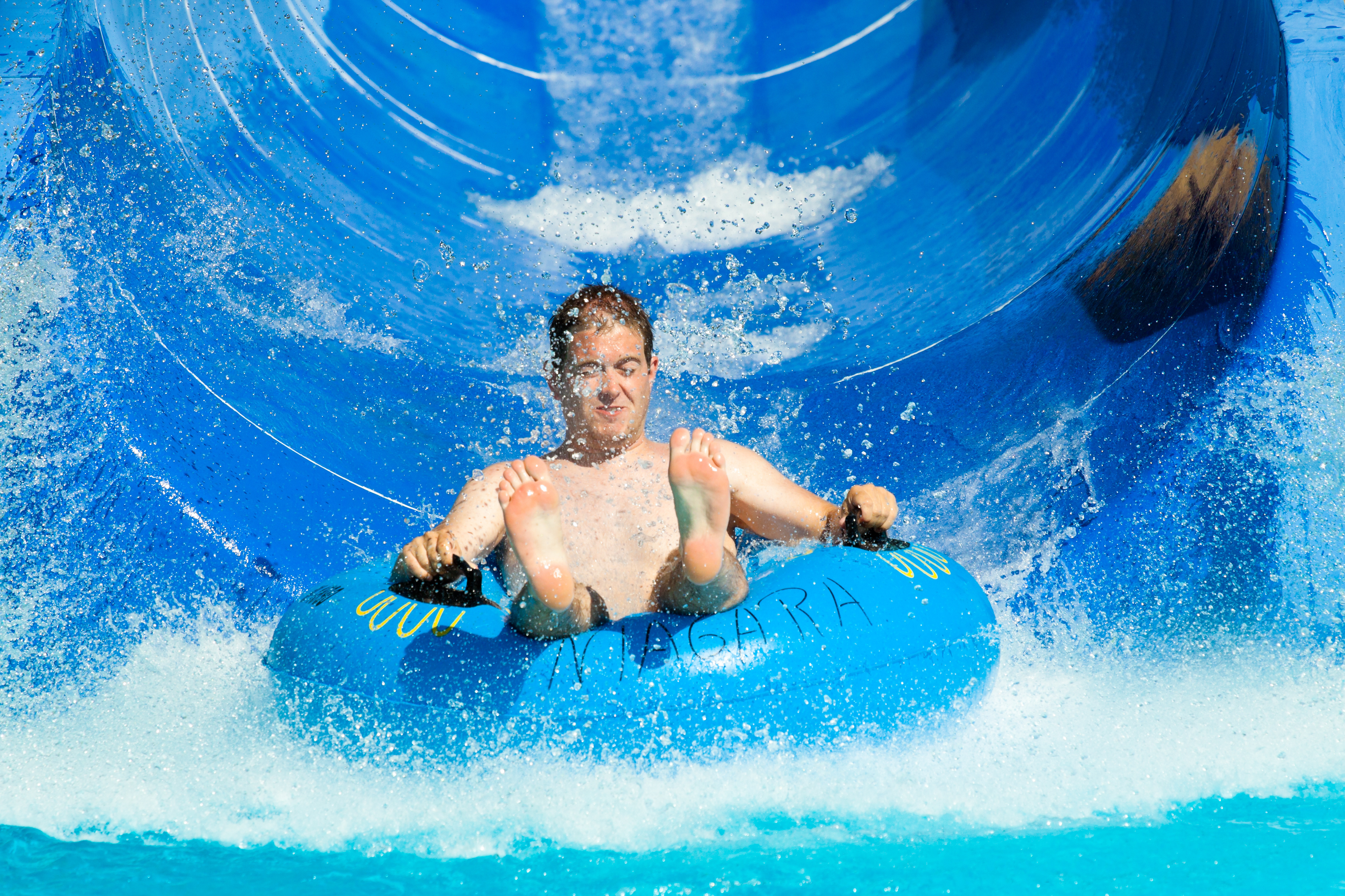 Man having fun, sliding at water park.